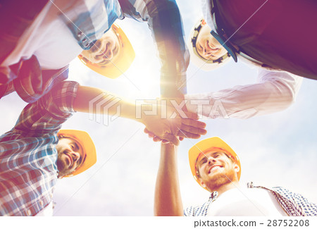 close up of builders in hardhats with hands on top 28752208