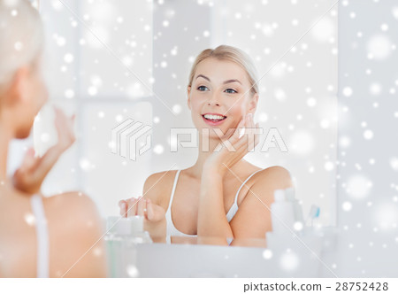 happy woman applying cream to face at bathroom 28752428