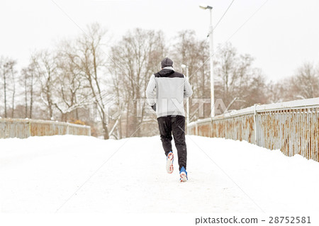 man running along snow covered winter bridge road 28752581