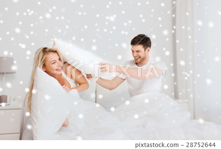 happy couple having pillow fight in bed at home happy couple having pillow fight in bed at home 28752644