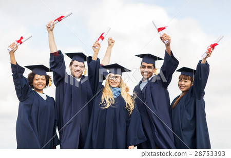 happy students in mortar boards waving diplomas 28753393