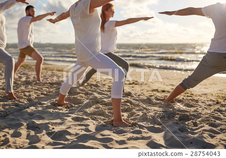 group of people making yoga exercises on beach 28754043
