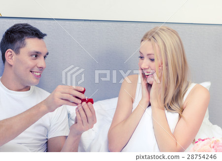 man giving woman little red box and ring in it 28754246