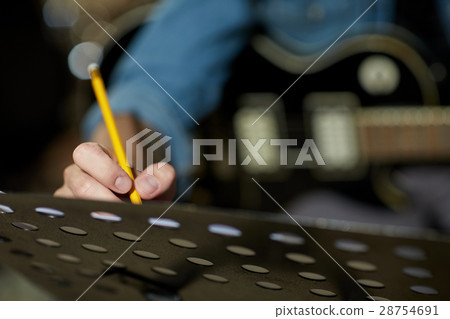 man with guitar writing to music book at studio 28754691