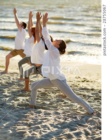 group of people making yoga exercises on beach 28755067