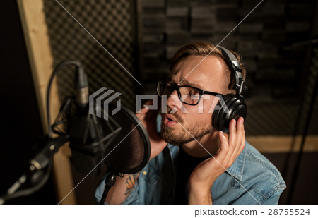 man with headphones singing at recording studio 28755524