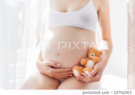 Pregnant woman with knitted toy teddy bear. 28762863