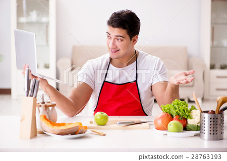 Man with laptop preparing food at the kitchen 28763193