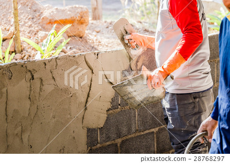 Worker plastering a wall using trowel 28768297