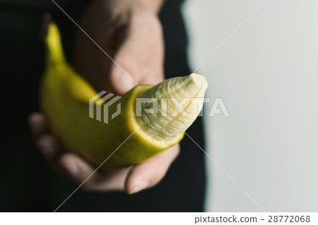 man with a banana with the tip of its skin removed man with a banana with the tip of its skin removed 28772068