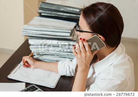 Female bookkeeper in glasses talking by phone Female bookkeeper in glasses talking by phone 28776672