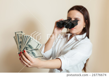 Woman looks through binoculars on money fan Woman looks through binoculars on money fan 28776674