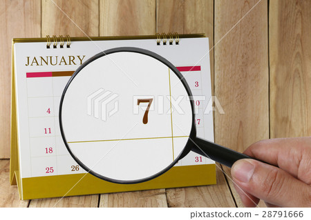 Magnifying glass in hand on calendar. Magnifying glass in hand on calendar. 28791666