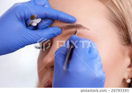 Plucking eyebrows by forceps for client. 28793393