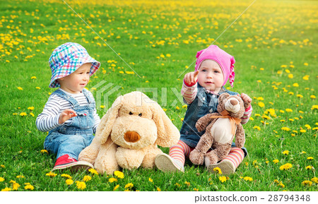 Little boy and girl in hats sitting on the field Little boy and girl in hats sitting on the field 28794348