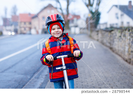 Cute little preschool kid boy riding on scooter 28798544