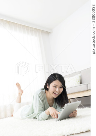 A young woman who controls a tablet lying on her lug lie on her face 28800058
