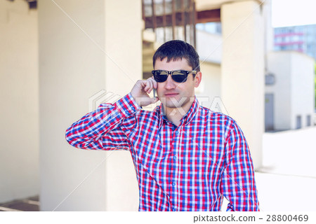 A man stands in the city in summer shirt, talking A man stands in the city in summer shirt, talking 28800469