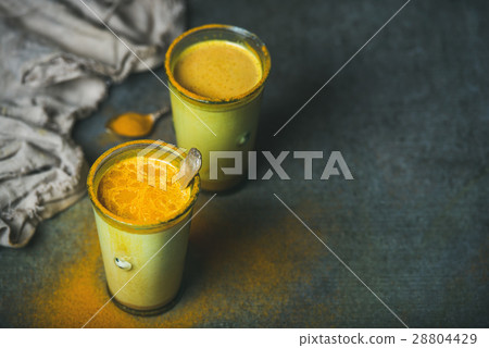 Golden milk with turmeric powder in glasses over 28804429