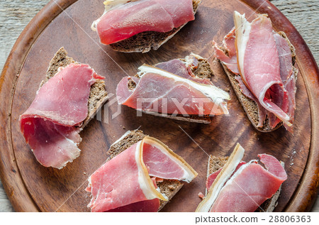 Slices of italian ham on the wooden board Slices of italian ham on the wooden board 28806363