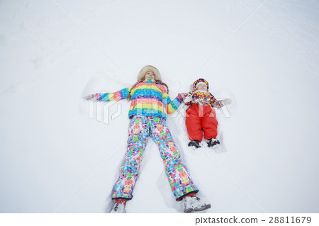 Daughter and mother are playing and lying in the snow in winter outdoors 28811679
