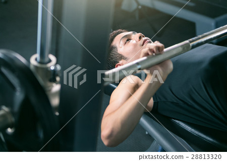 Man lifting dumbbell weights while lying down. 28813320