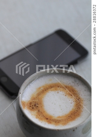 A homemade fluffy cappuccino with a smartphone A homemade fluffy cappuccino with a smartphone 28816372