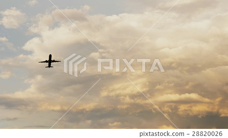 Passenger airplane taking off at sunset against Passenger airplane taking off at sunset against 28820026