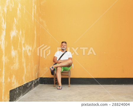 man sitting on a wooden chair in a shabby room  28824004