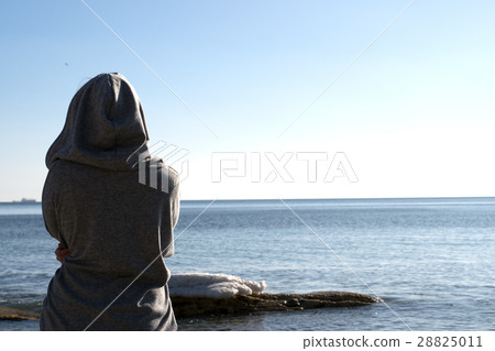 Young beautiful girl in  hood near the sea. Sunset 28825011