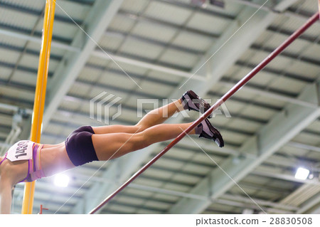 Young athletic woman vaoulting over bar with pole Young athletic woman vaoulting over bar with pole 28830508