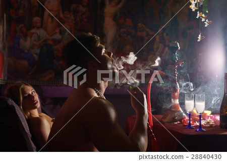 Young sexy athletic tattooed man smoking hookan Young sexy athletic tattooed man smoking hookan 28840430