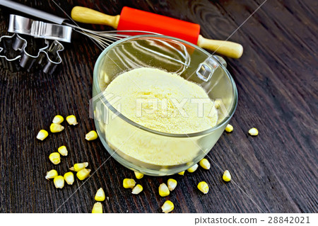 Flour corn in cup with grains on dark board Flour corn in cup with grains on dark board 28842021