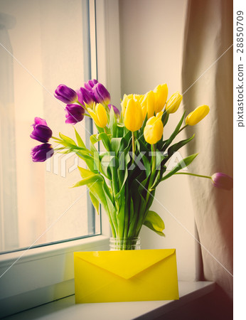 bunch of tulips and envelope on windowsill 28850709