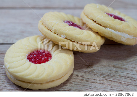 Sweet cookies with cream and jam on wood 28867868