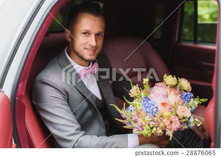 Groom with bouquet in the wedding car 28876065