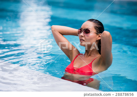 Woman wearing red swimsuit and sunglasses sitting 28878656