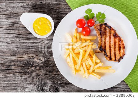 grilled pork chops on dish with french fries 28890302