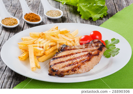 grilled pork chops on dish with french fries 28890306