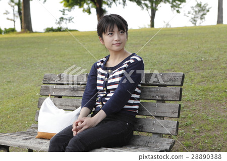 A young woman sitting on a bench 28890388