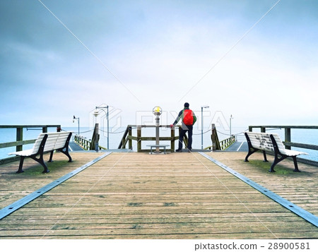 Tourist with red backpack on wooden sea pier Tourist with red backpack on wooden sea pier 28900581