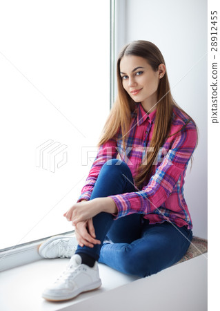 Young smiling woman sitting on window sill 28912455