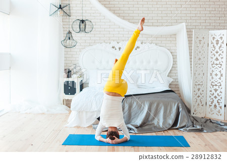 Woman is making a stand on her head. 28912832