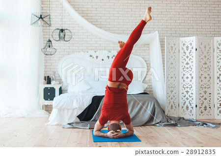 Morning in the bedroom a man stands on his head. 28912835