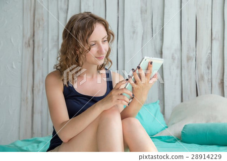 Young curly woman lying in the bed with tablet pc. 28914229