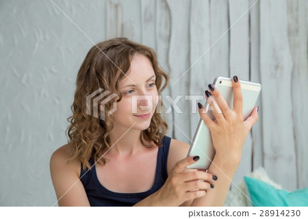 Young curly woman lying in the bed with tablet pc. Young curly woman lying in the bed with tablet pc. 28914230