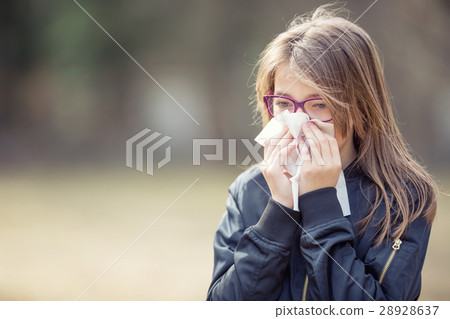 Girl with allergy symptom blowing nose. Girl with allergy symptom blowing nose. 28928637