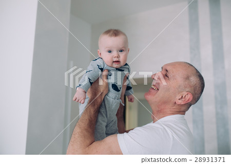 Grandfather holds granddaughter on hands 28931371