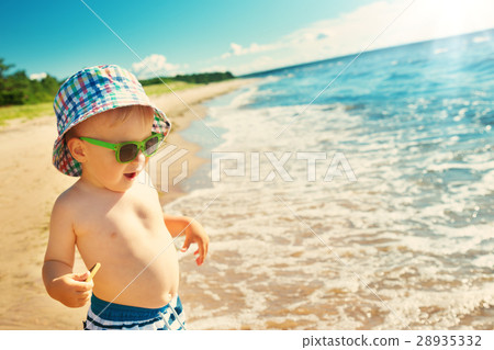 little boy walking at the beach in summer hat 28935332