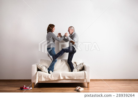 Beautiful senior couple standing on couch, dancing Beautiful senior couple standing on couch, dancing 28939264